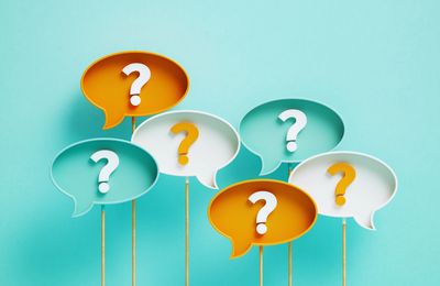 Colorful speech bubbles with question marks on sticks against a blue background.