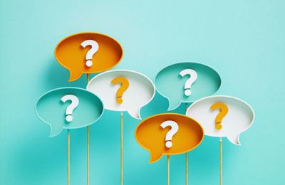 Colorful speech bubbles with question marks on sticks against a blue background.