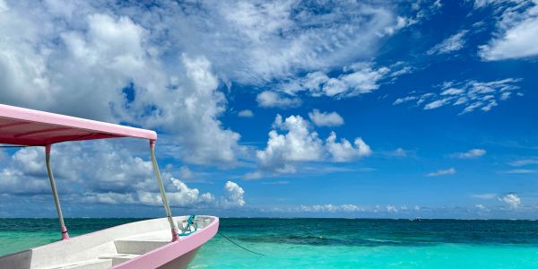 Boat on clear turquoise water under blue sky.