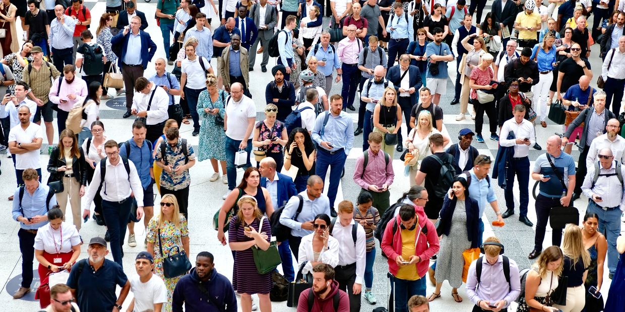 A large diverse crowd of people standing in a busy indoor public space.