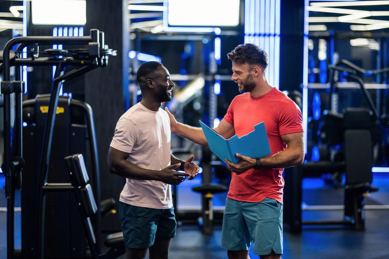 Male personal trainer doing a training consultation with his client in the health club.
