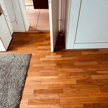 Wooden floor with an open door and a gray carpet.