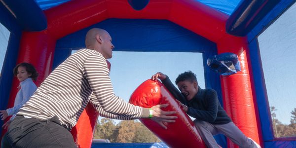 Man and boy playing together on an inflatable bounce house.