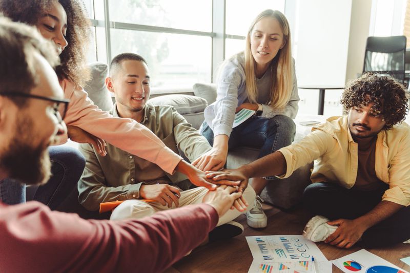 Diverse team of professionals is joining hands in a circle, symbolizing their unity and teamwork in achieving shared goals