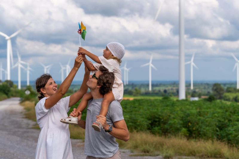 Family Enjoying a Day Near Wind Turbines Symbolizing Clean Energy and Sustainable Electricity Production
