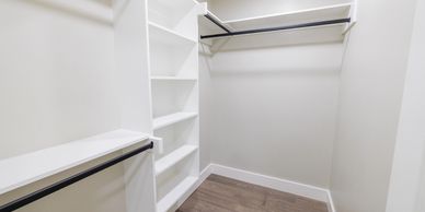 Empty walk-in closet with white shelves and hanging rods.