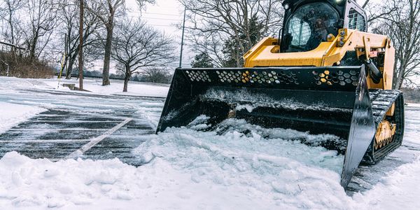 Bulldozer clearing snow in a parking lot.