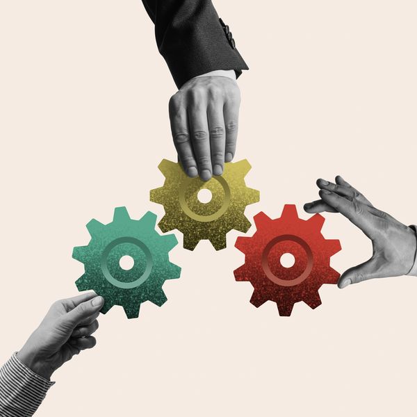 Hands holding colorful gears symbolizing teamwork and collaboration.