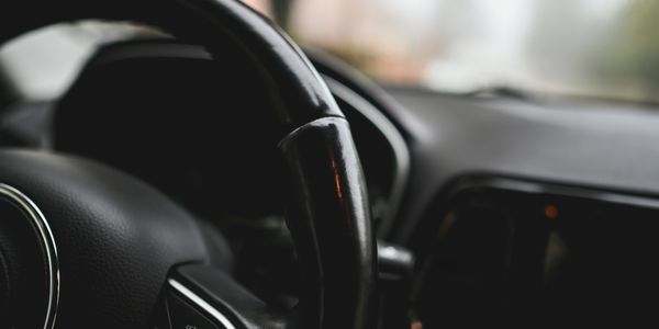 Close-up of a black car steering wheel with control buttons.