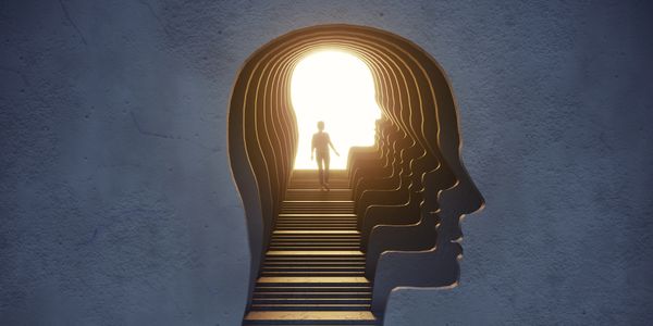 A person walks up stairs shaped like a human head silhouette towards bright light.
