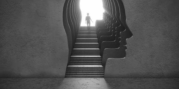 Person walking up stairs shaped like successive human heads inside a head silhouette.