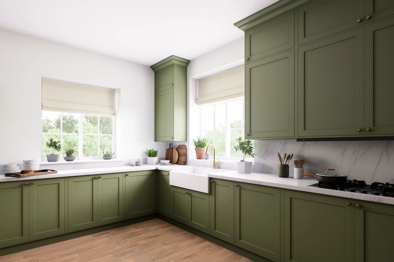 A modern kitchen with green cabinetry, a farmhouse sink, and plenty of natural light from the windows
