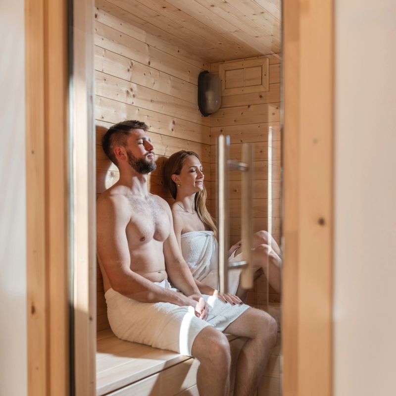 Attractive young couple sitting and relaxing in a sauna room in the health spa. Romantic getaway and weekend trip concepts.