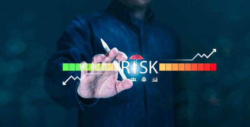 A man points to a risk management icon (person with umbrella), with a color-coded risk indicator. Concept for illustrating business strategy, planning and risk assessment.