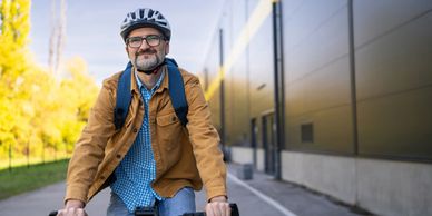 Man wearing a helmet biking on a pathway beside a building.