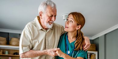Nurse assisting elderly man standing up from wheelchair.