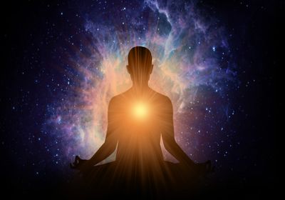 Silhouette meditating with glowing light and cosmic background.