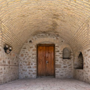 Stone archway with wooden door and lantern light fixture.
