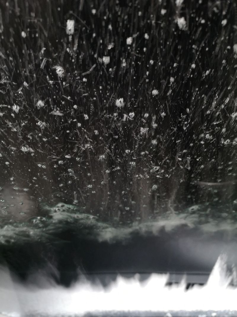 Rotating brush in the car wash against the windshield of the car. Seen from inside and very close.