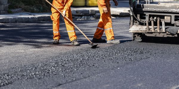 Workers paving a road with asphalt.