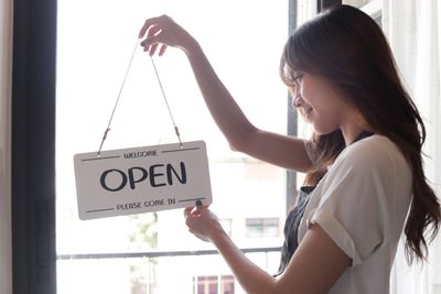 woman changing shop open/close sign 
