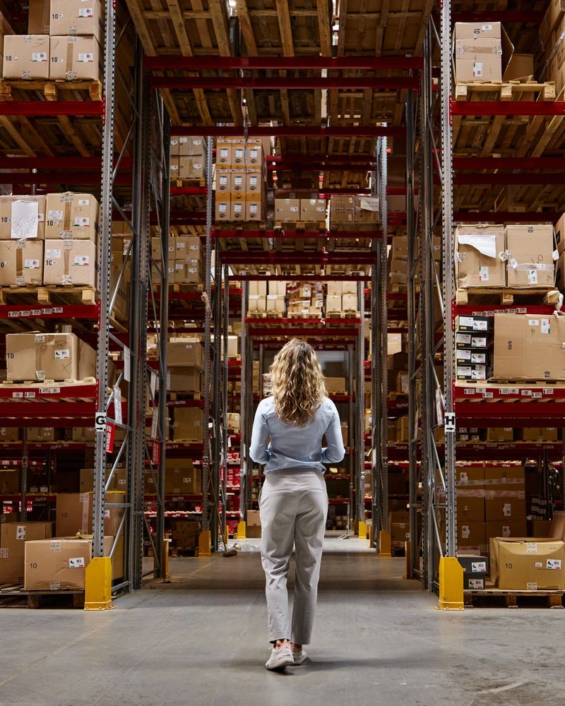 Rear view of a female inspector walking through distribution warehouse.