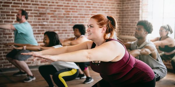 A diverse group exercising together in a fitness class performing squats.
