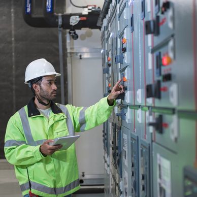 Engineer in safety gear operating control panels in an industrial setting.