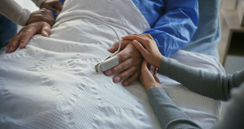 Holding hands, patient and family by hospital bed for support, sick and empathy for wellness. People, care and console for person with connection, love and help with comfort for recovery at clinic