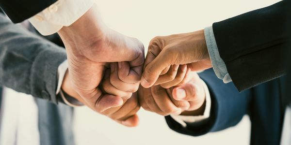 Four business people fist bumping in a team-building gesture.