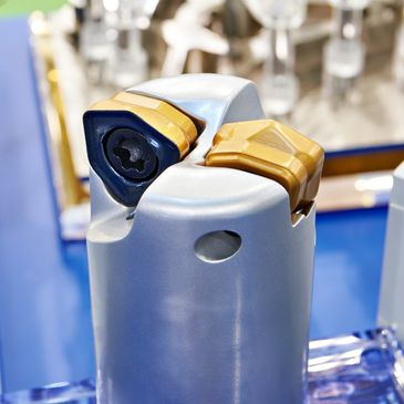 Close-up of a metal cutting tool with gold and black inserts.