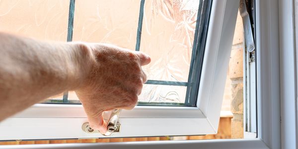 Person opening a frosted glass window.