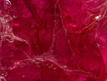 Close-up of vibrant red crystalline or glass-like textured surface.