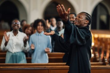 Man passionately leading worship in church with congregation engaged.