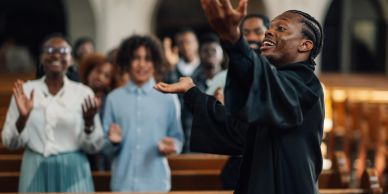 Man passionately singing in church with audience applauding.
