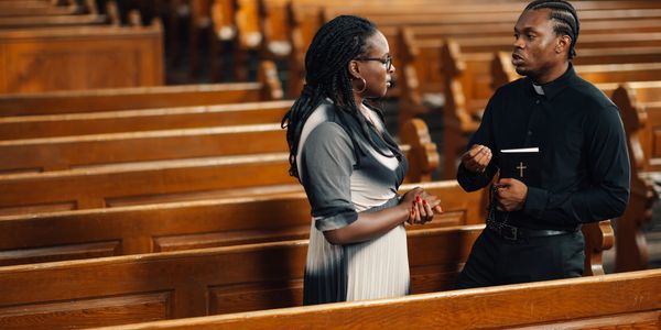 A priest talking to a woman inside a church.