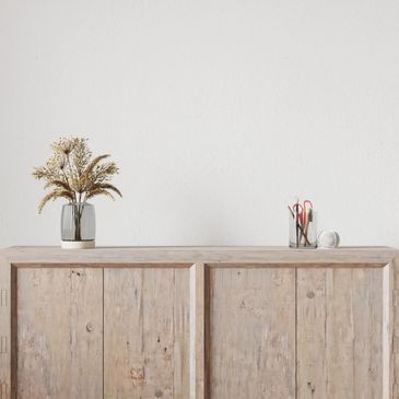 Minimalist wooden cabinet with decorative vase and stationery.