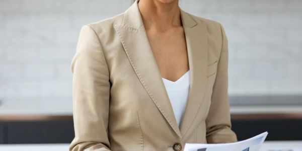 Professional woman in a beige blazer reviewing documents.