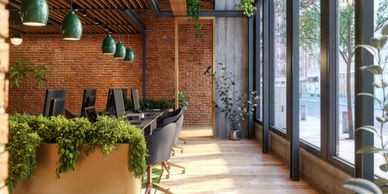 Modern office space with brick walls, green plants, and large windows providing natural light.