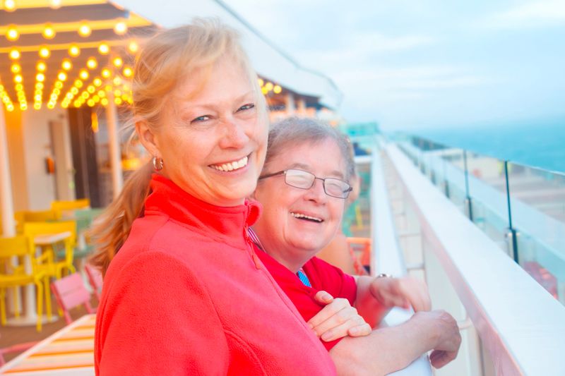 Two women enjoy the view on deck of a cruise ship at the Gulf of Mexico. They enjoy the sunset and the warm breeze of the sea.