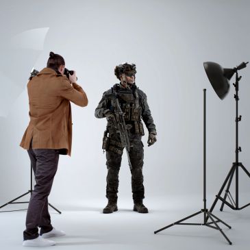 Photographer taking a picture of a soldier in full gear in a studio.
