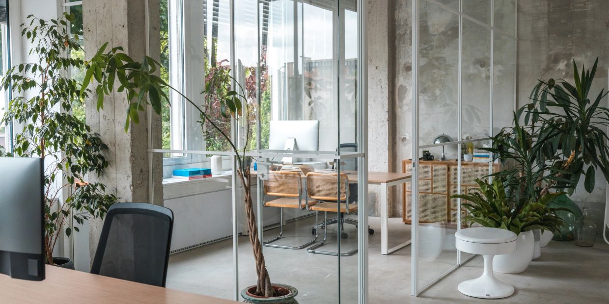 Modern office space with glass partitions and plants.