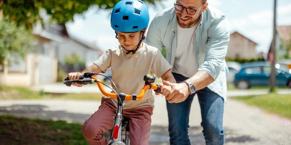 Father helping child learn to ride a bike with safety helmet. Make America safe. National security.