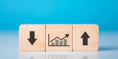 Wooden blocks with arrows and a rising graph symbol on blue background.