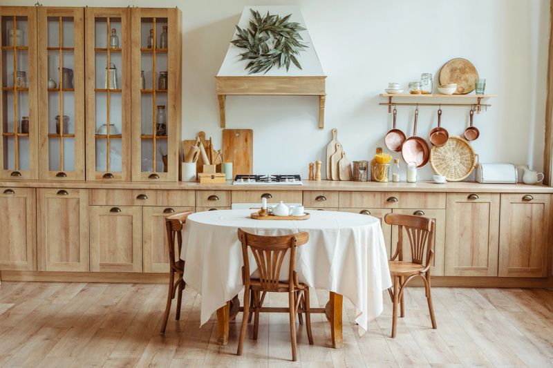 Wooden kitchen cabinets and shelves creating a warm and inviting atmosphere in a cozy farmhouse style kitchen with round dining table