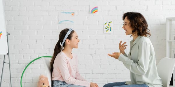Woman and girl smiling and talking indoors.