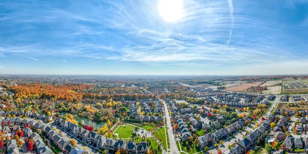 A suburban neighborhood with colorful autumn trees under a bright sun.