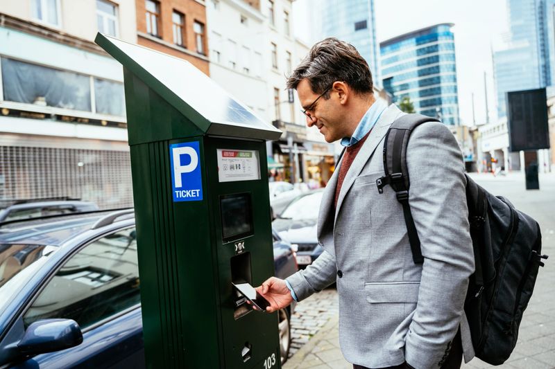 Man in business attire with backpack paying street parking