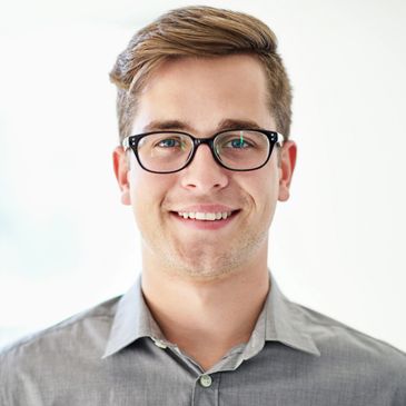 Smiling young man with glasses and a gray shirt.