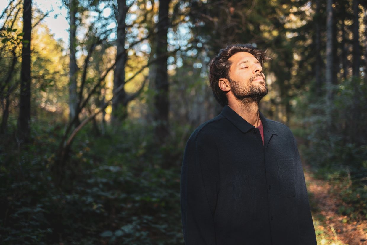 Man enjoying peaceful moment in sunlit forest.